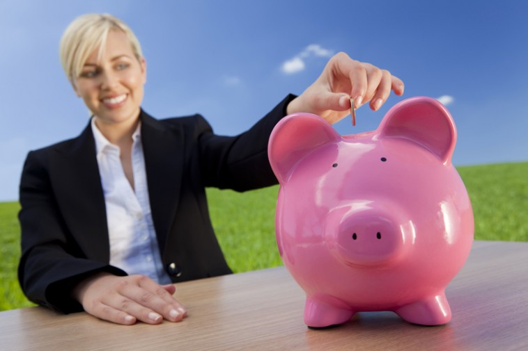 Woman putting penny into pink piggy bank