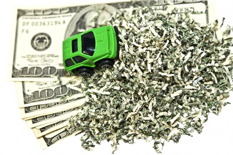 Small green model car on a pile of shredded money